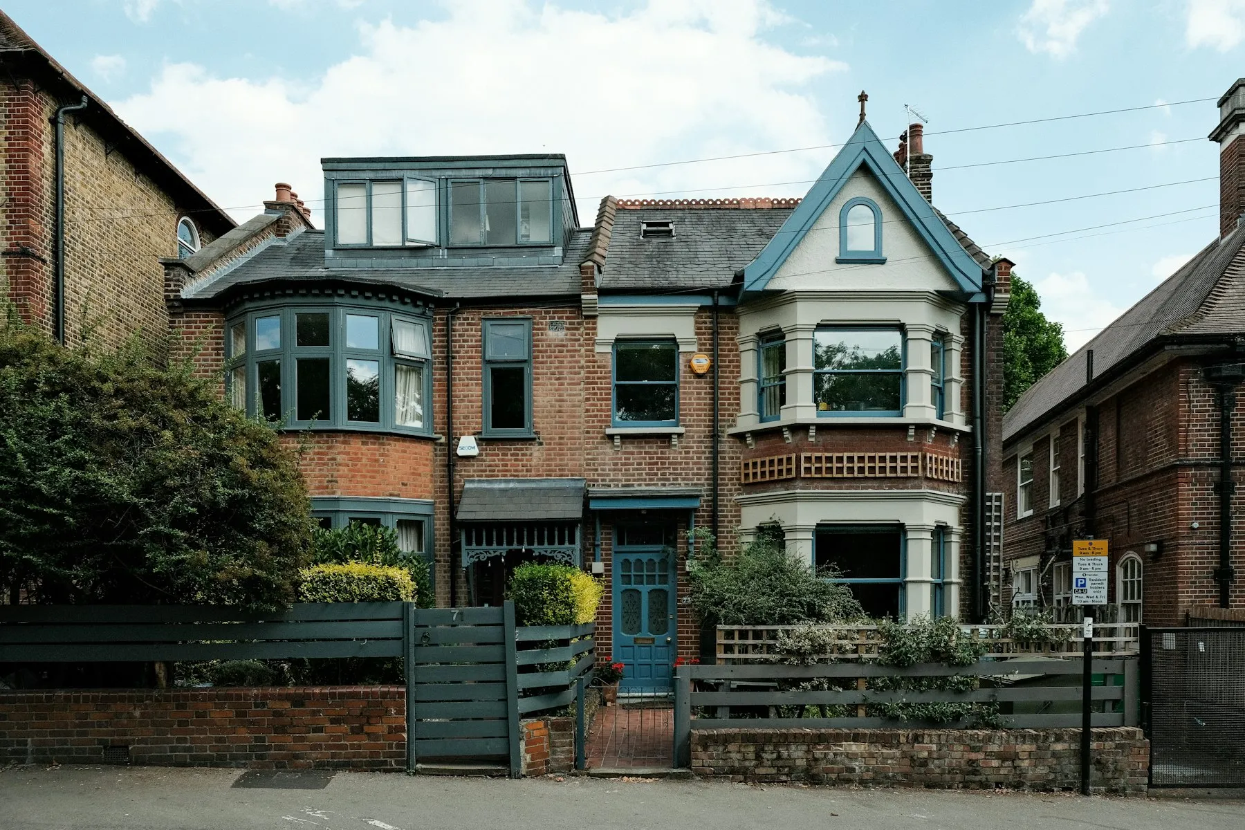 The front of the house, a red-brick Victorian villa with a bay window and a turret