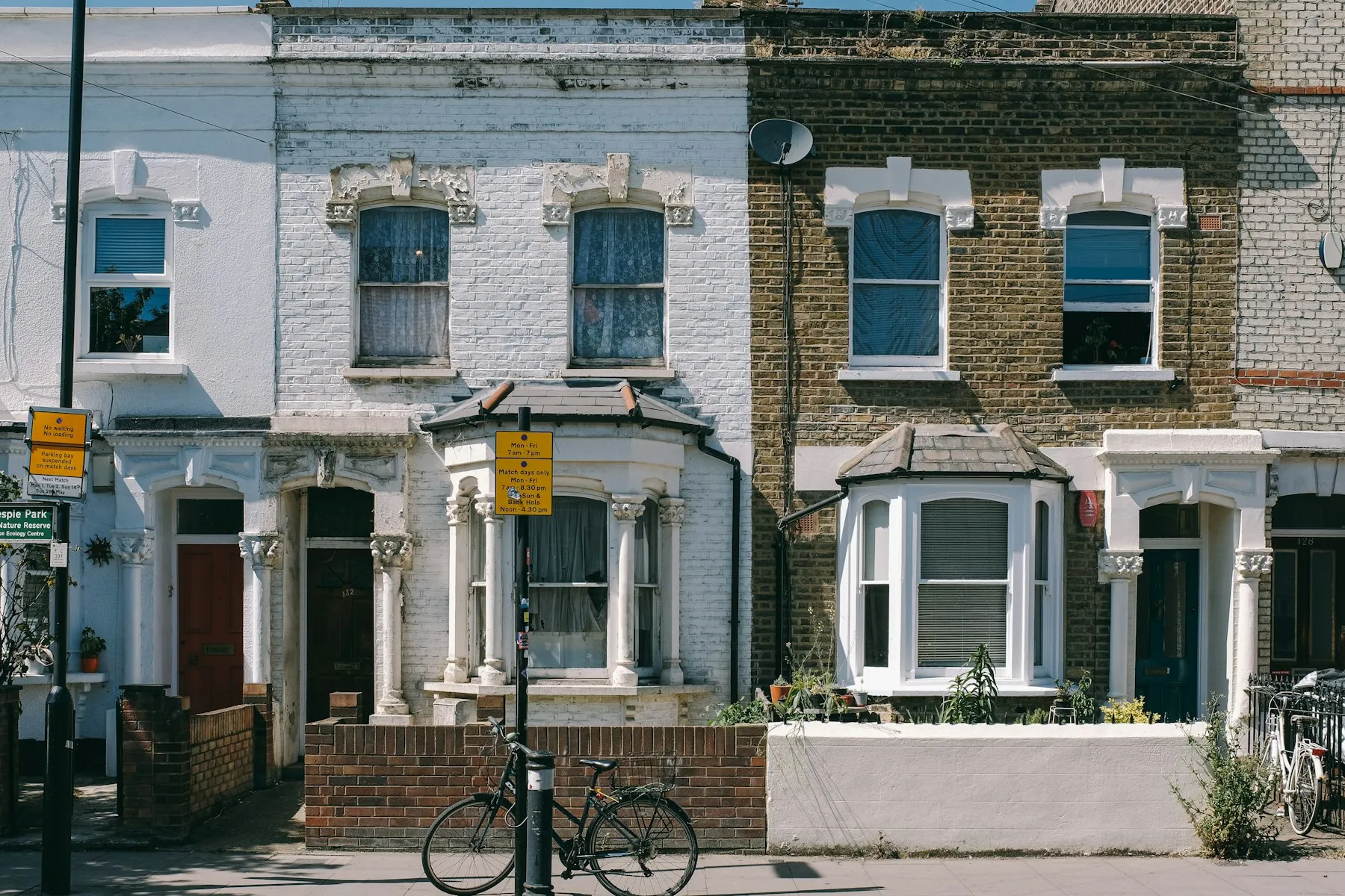 A row of Victorian terraced houses with bay windows and front gardens