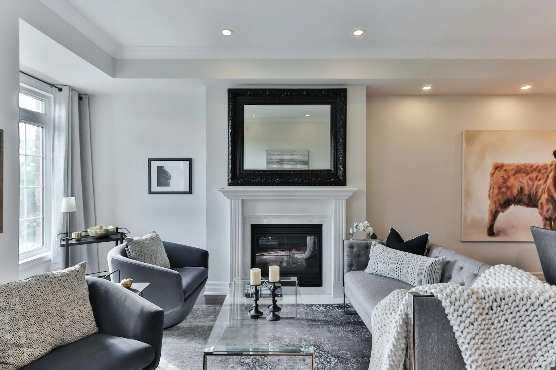 The reception room, with a white fireplace, a grey sofa and a framed mirror