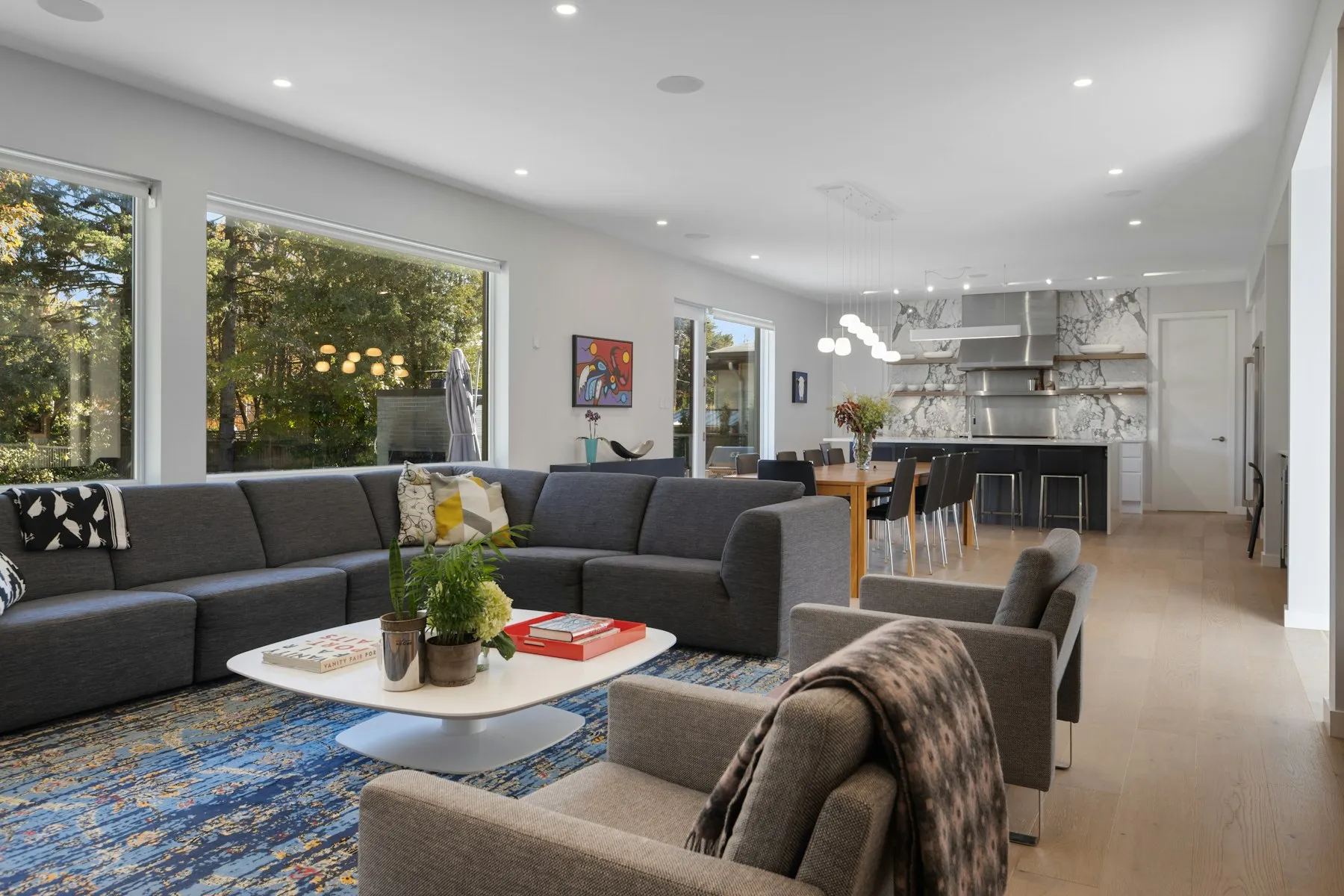 The living room, with a large grey sectional sofa and windows onto the garden