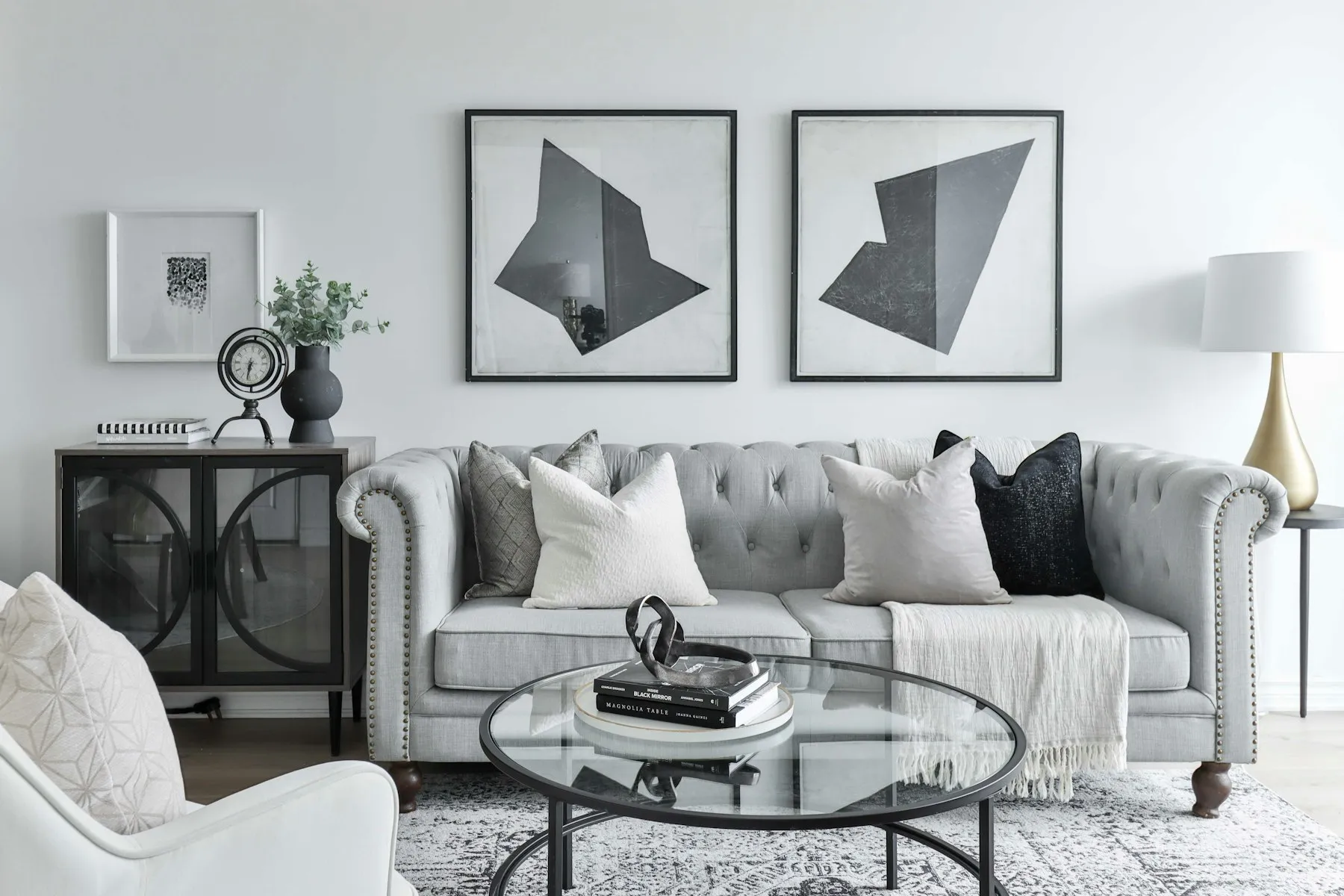 The sitting area, with a tufted grey sofa and two geometric prints