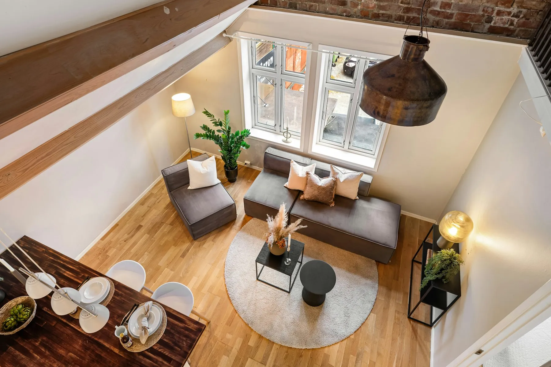The reception room from above, with a grey sofa, a round rug and tall windows