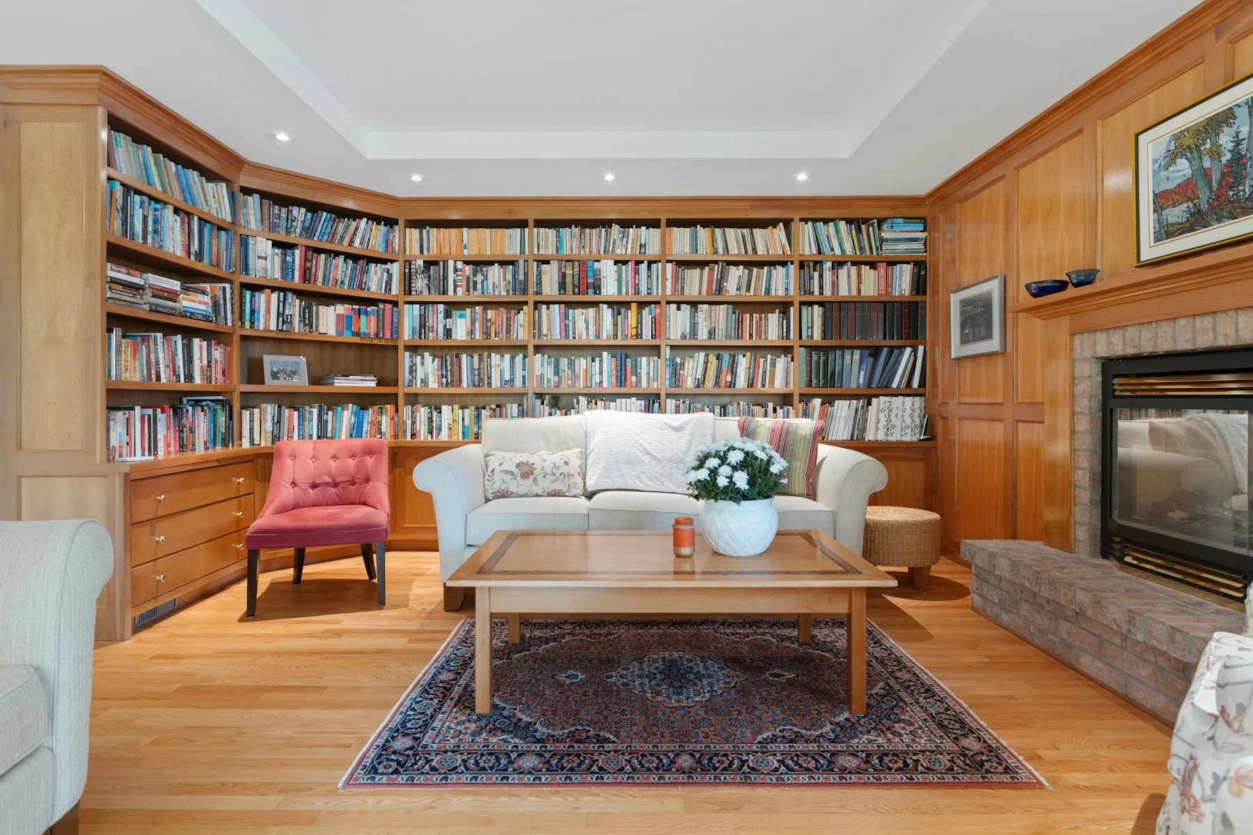 The library, with floor-to-ceiling bookshelves, a fireplace and a cream sofa