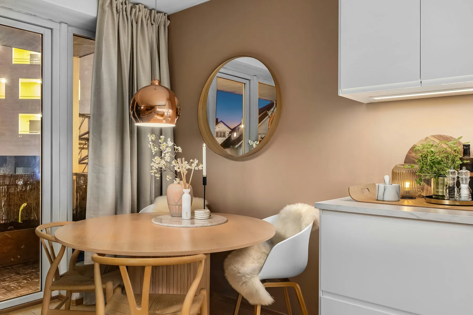 The dining corner, with a round oak table and a brass mirror