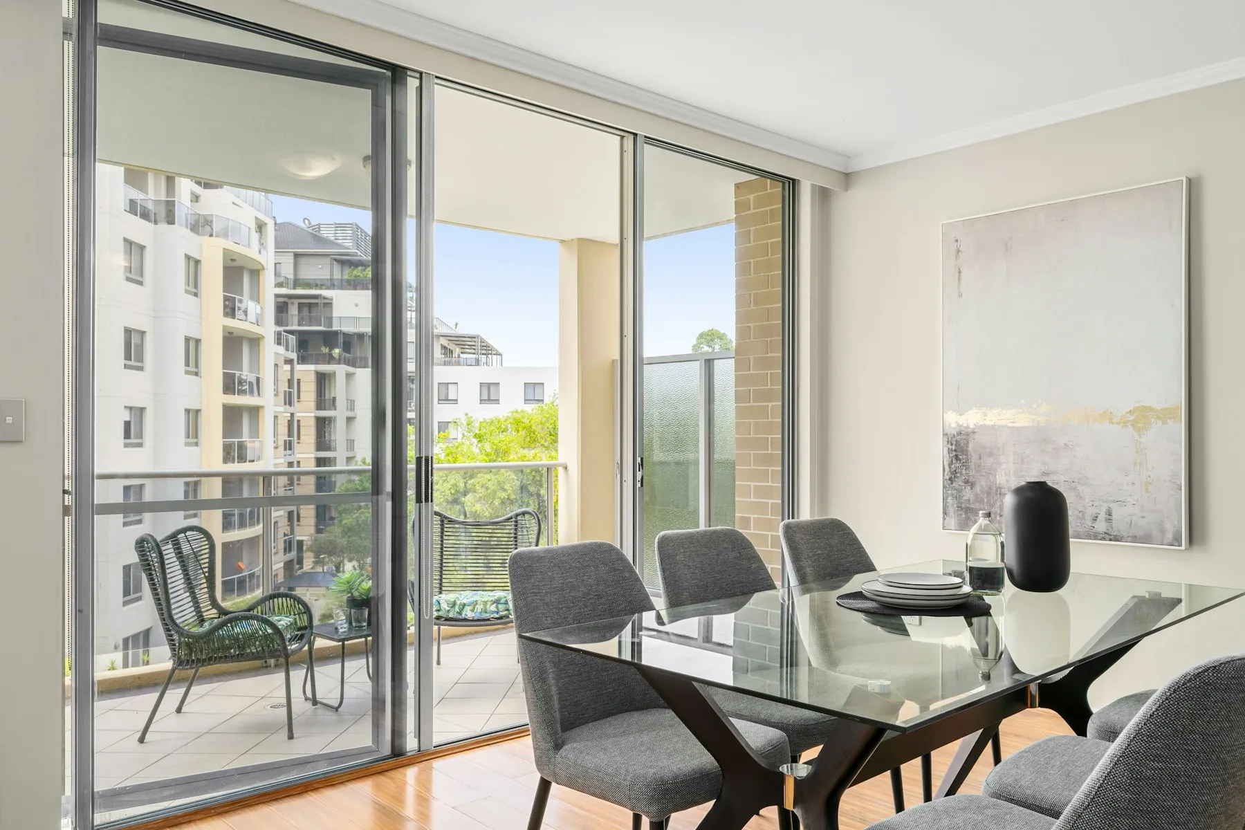 The dining area, with a glass table and sliding doors to the balcony