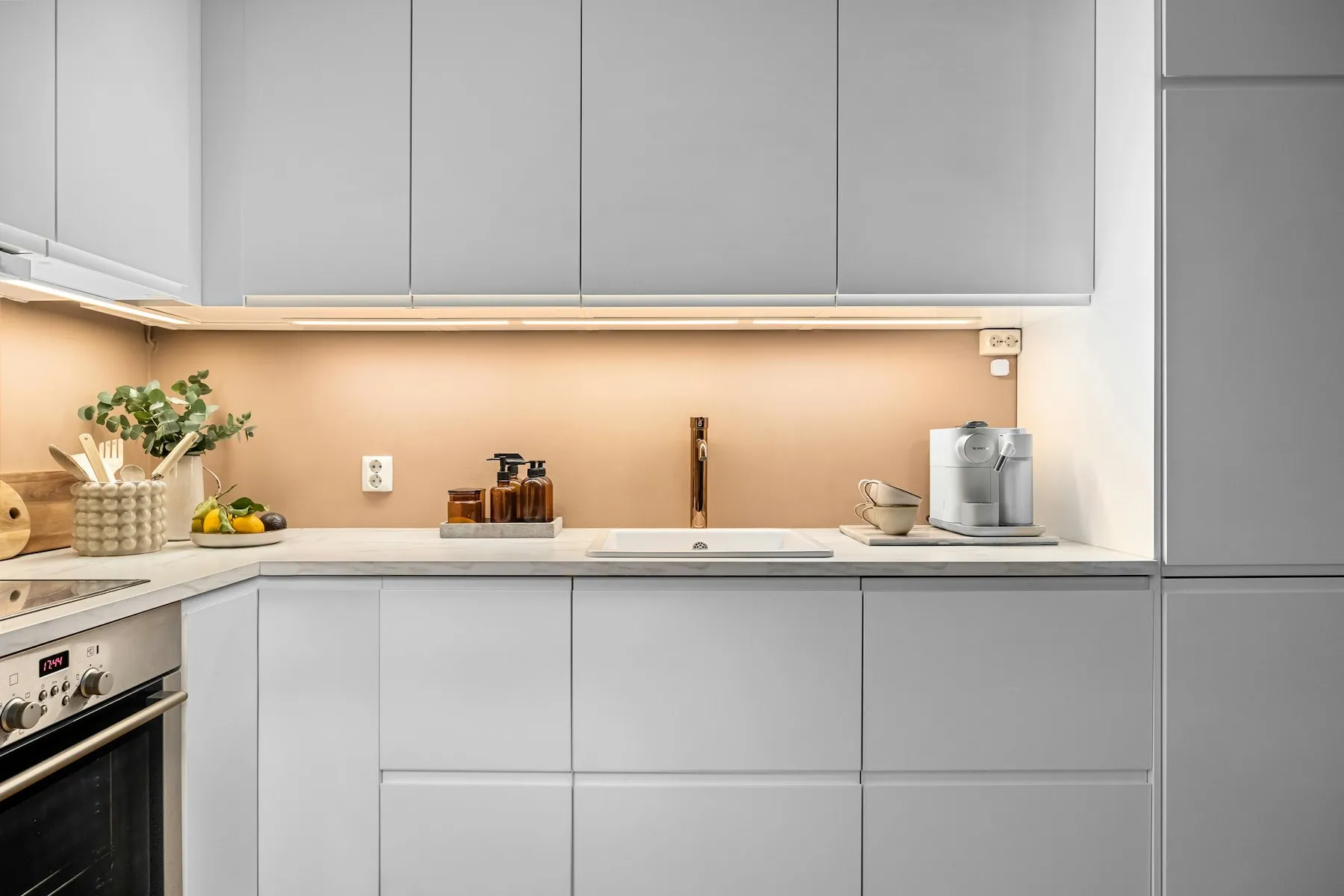 The kitchen, with white handleless cabinets and under-cabinet lighting
