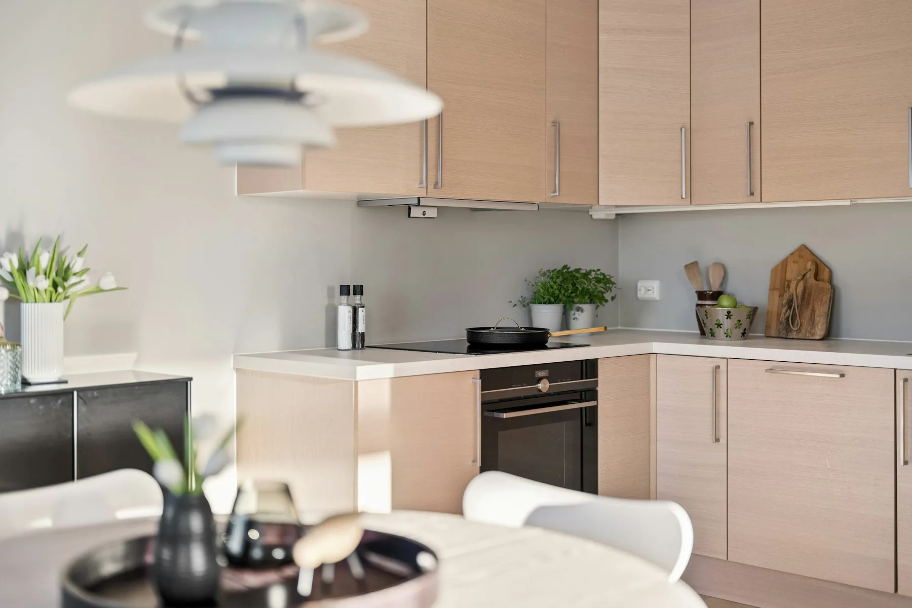 The kitchen, with pale wood cabinets and a white worktop