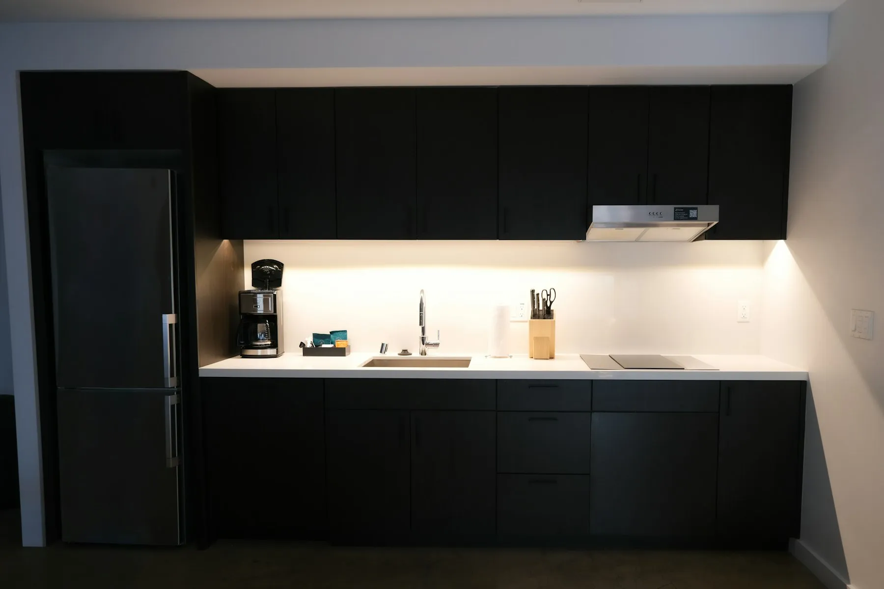 The kitchen, with dark handleless cabinets and a long white worktop