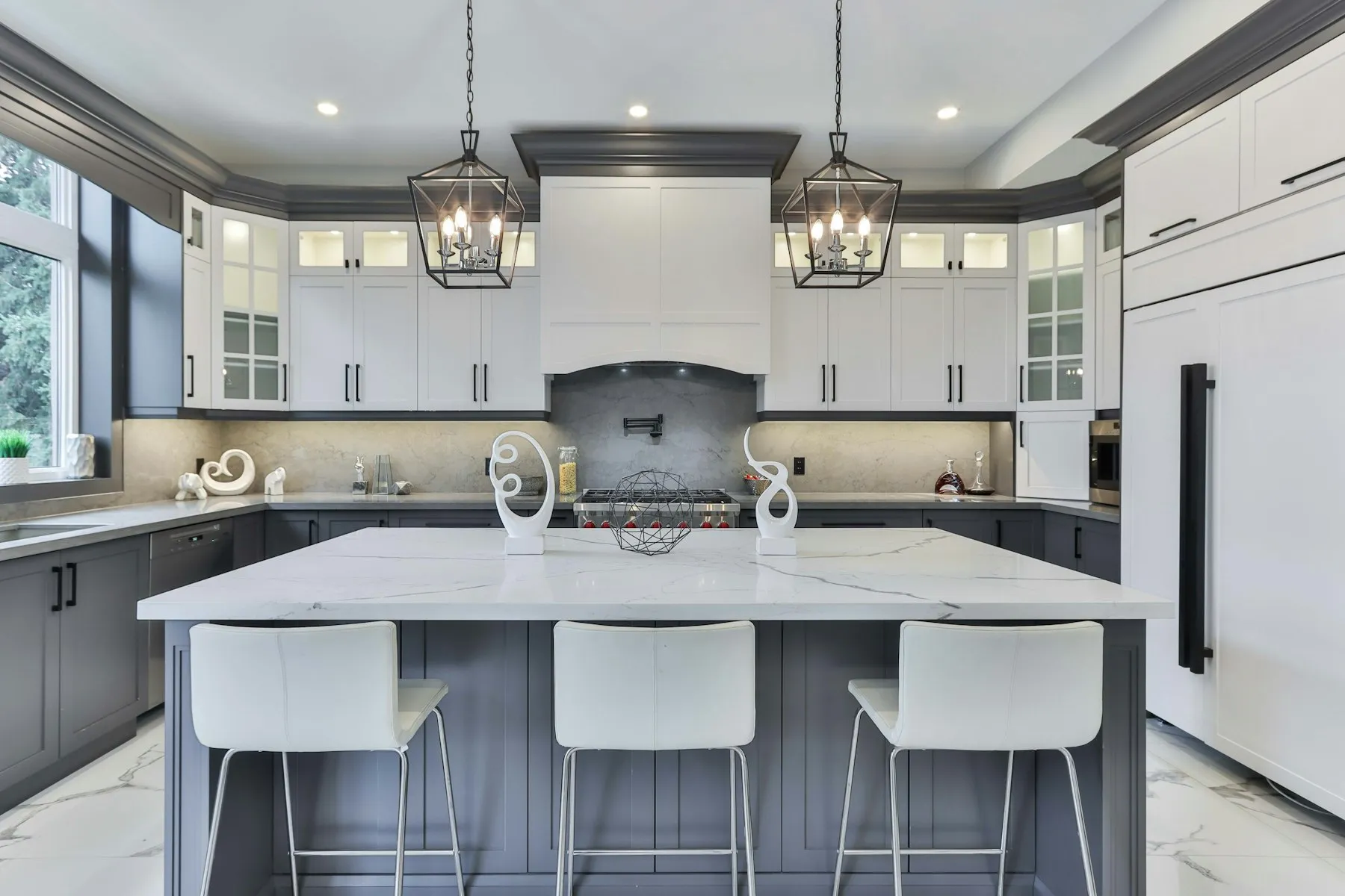 The kitchen, with a white island, lantern pendants and bar stools