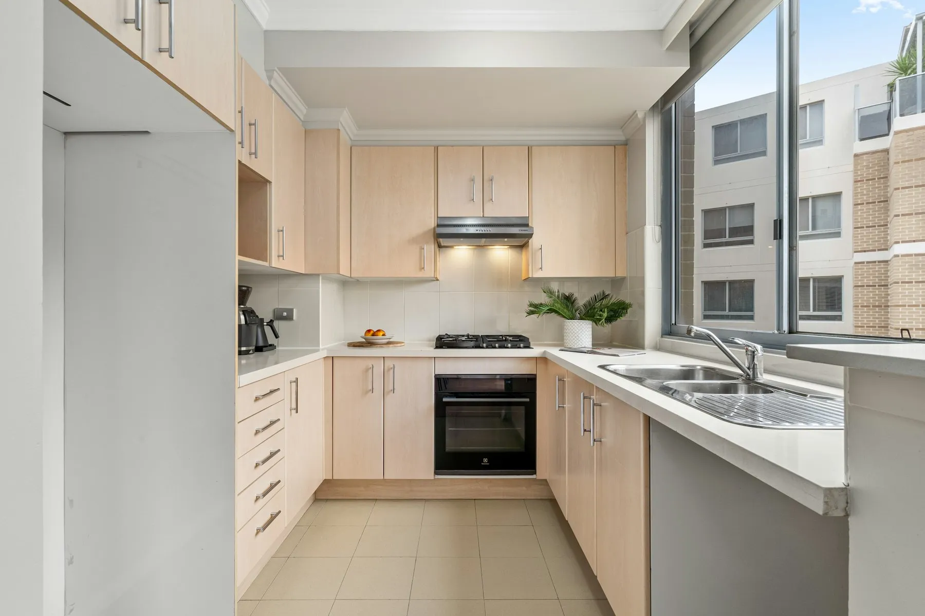 The kitchen, with pale wood cabinets and a window over the sink