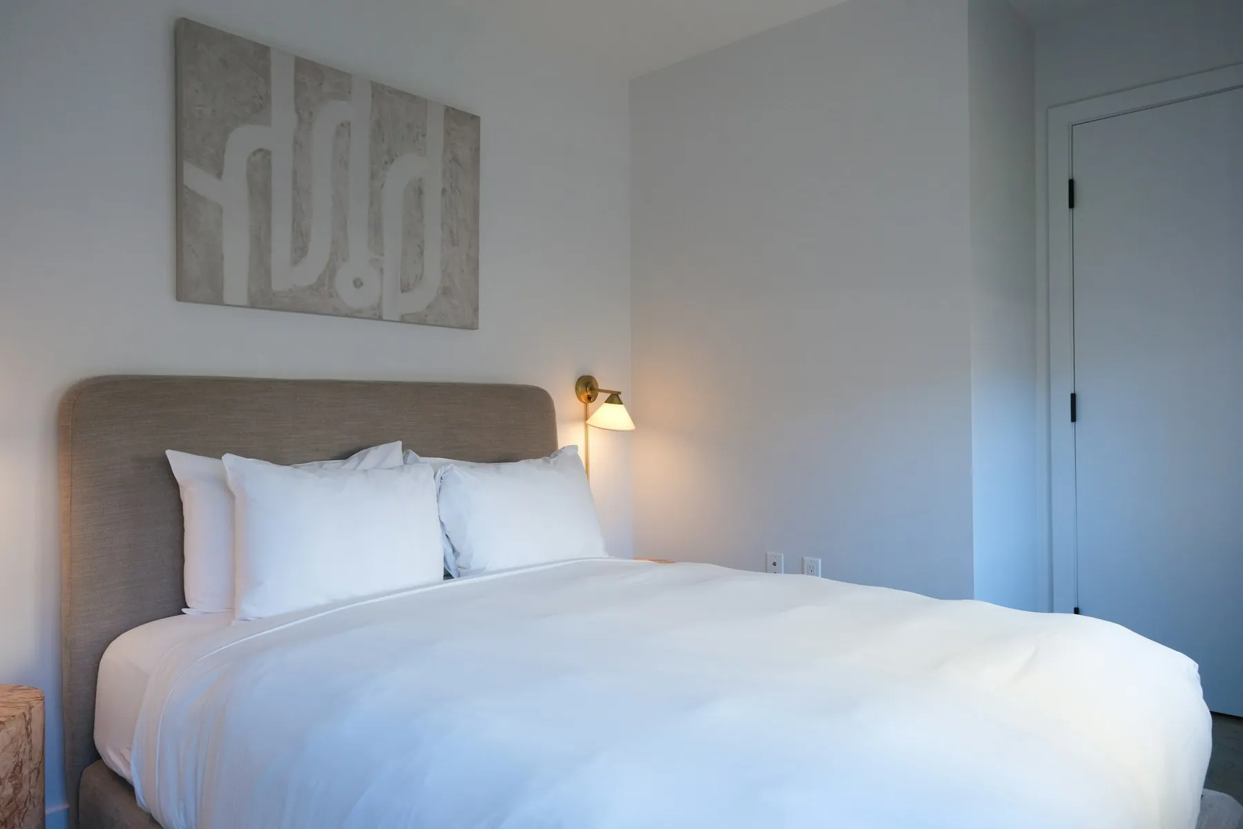 The main bedroom, with a large upholstered bed and pale grey walls