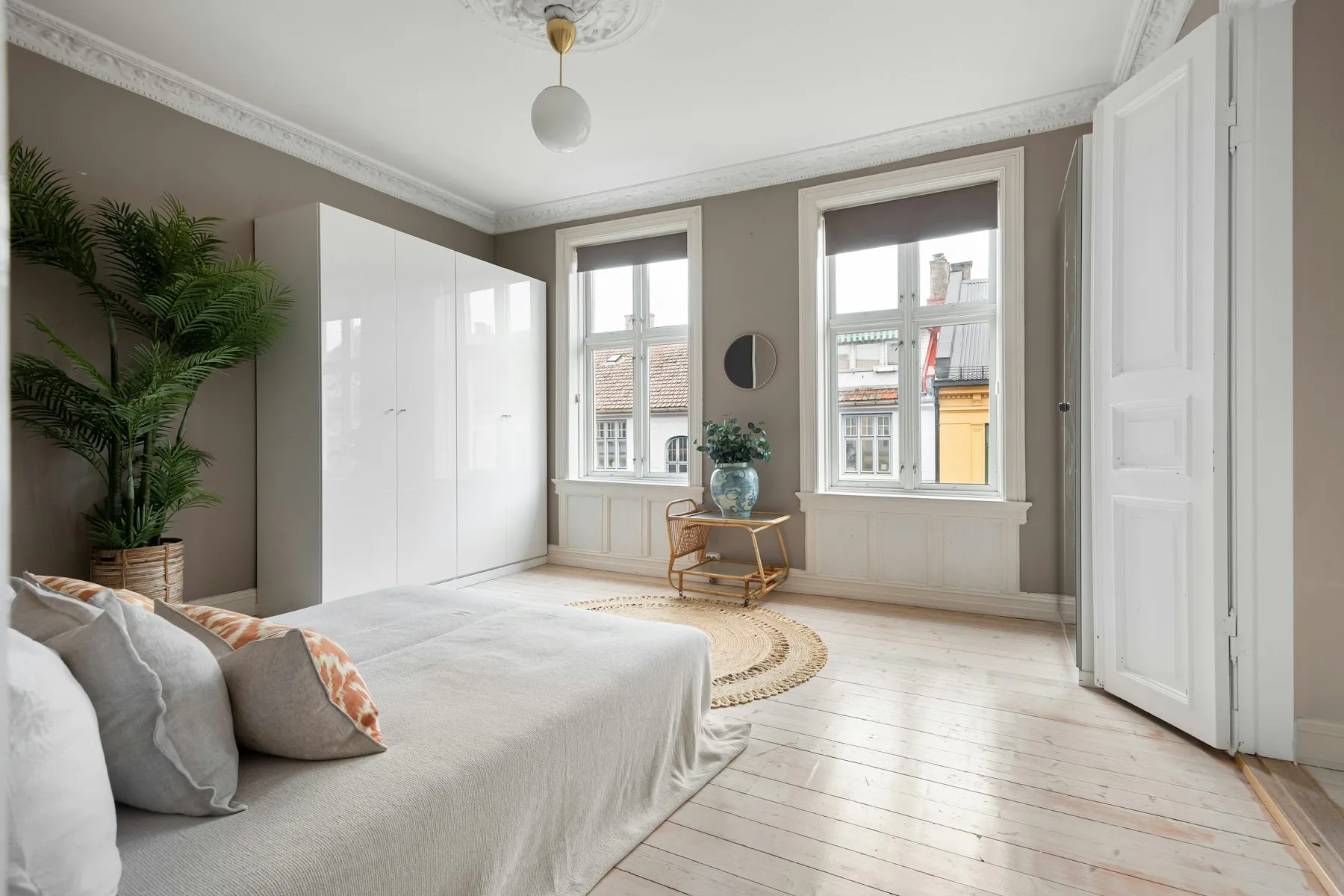 The principal bedroom, with tall windows and a large potted palm