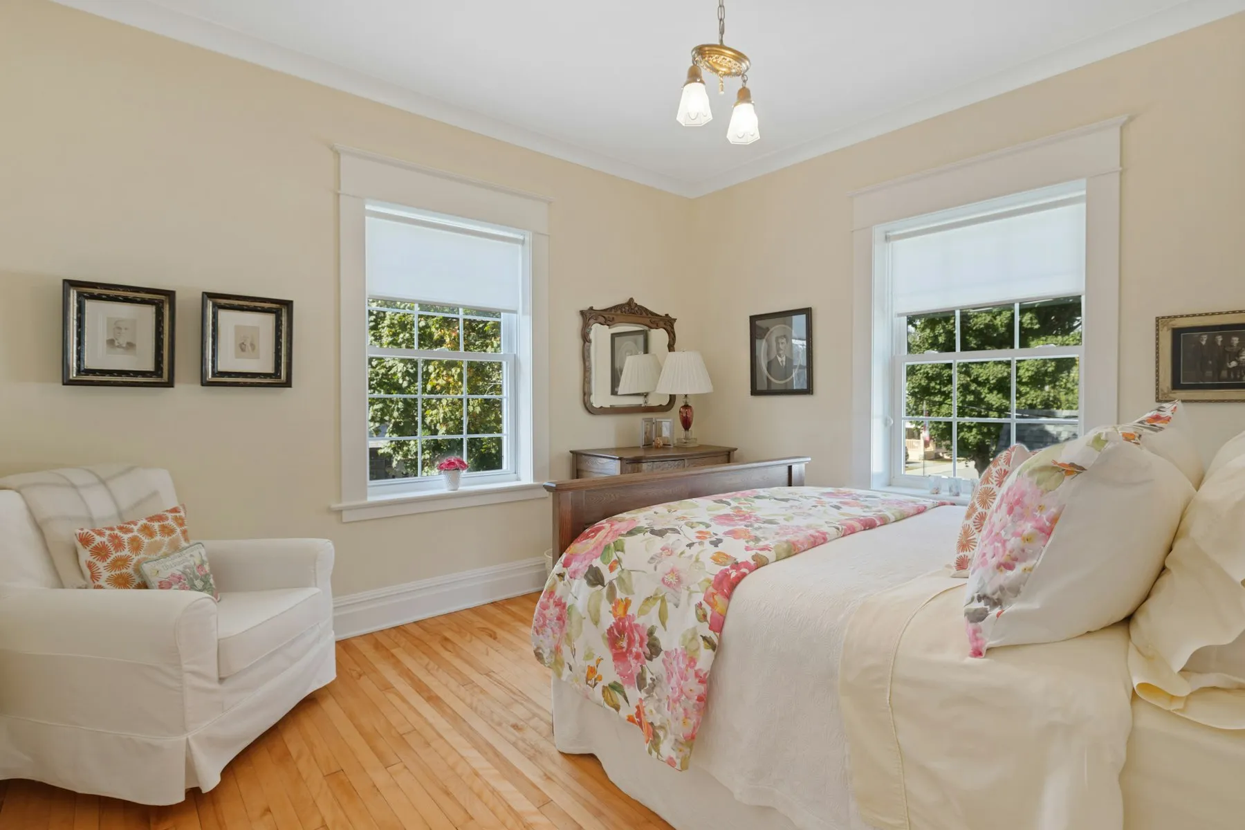 The principal bedroom, with a floral bedspread and two sash windows