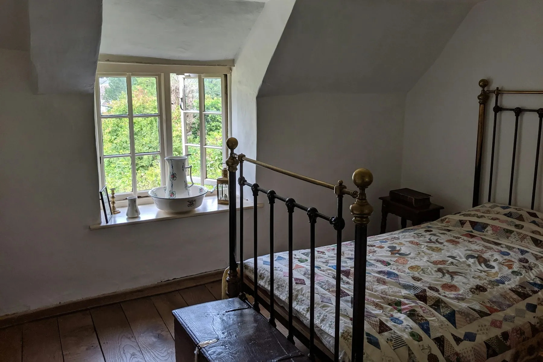 The bedroom, with an iron bedstead and a window over the garden