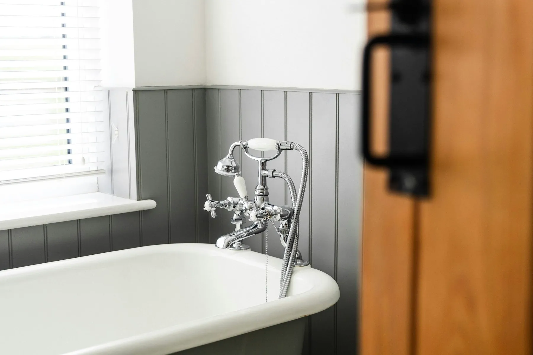 The bathroom, with a roll-top bath and dark panelled walls