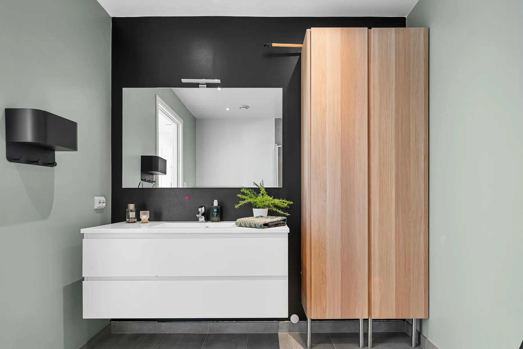 The bathroom, with a white vanity and a wooden storage cabinet