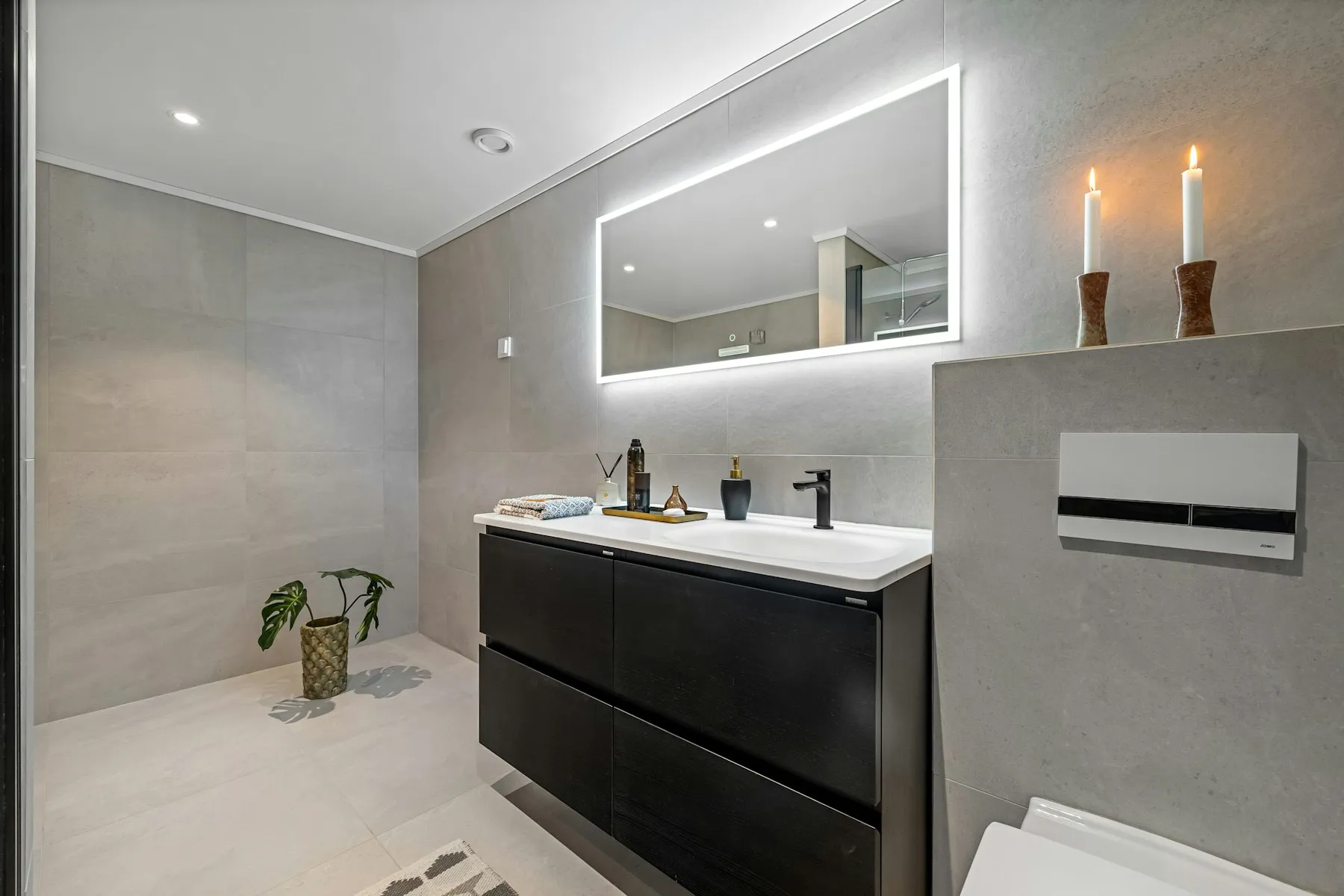 The bathroom, with a backlit mirror and a dark wood vanity