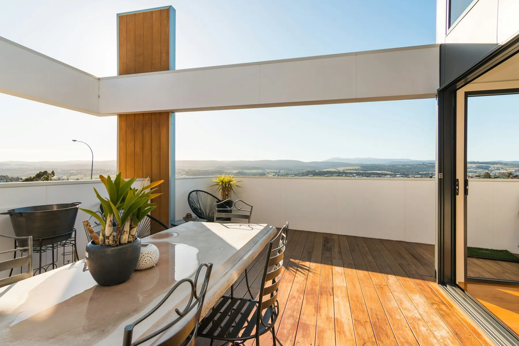 The terrace, with a timber deck, a table and chairs and a glass balustrade