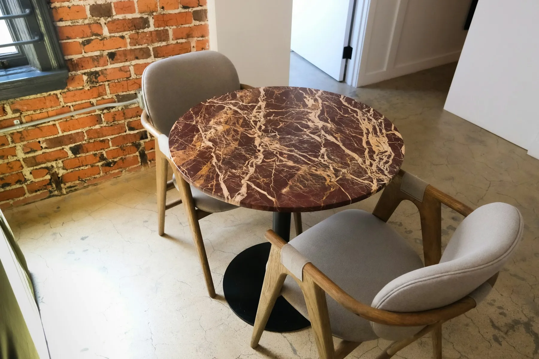 The dining corner, with a marble table against the exposed brick wall