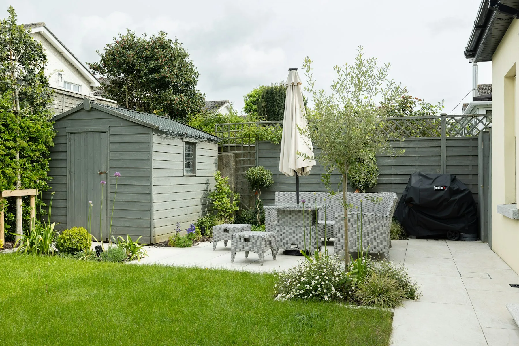 The garden, with a lawn, a paved terrace and a painted shed