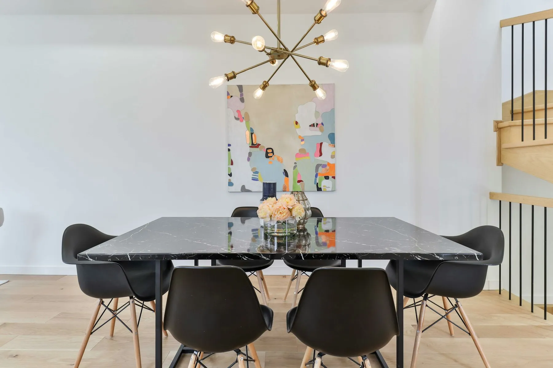 The dining area, with a black table, moulded chairs and a sputnik chandelier