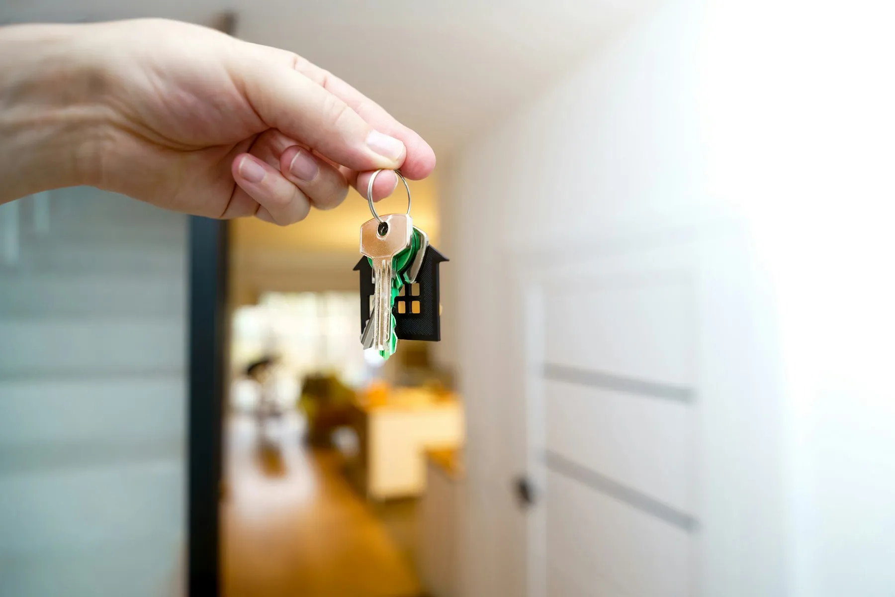 A hand holding a bunch of house keys in front of an open door