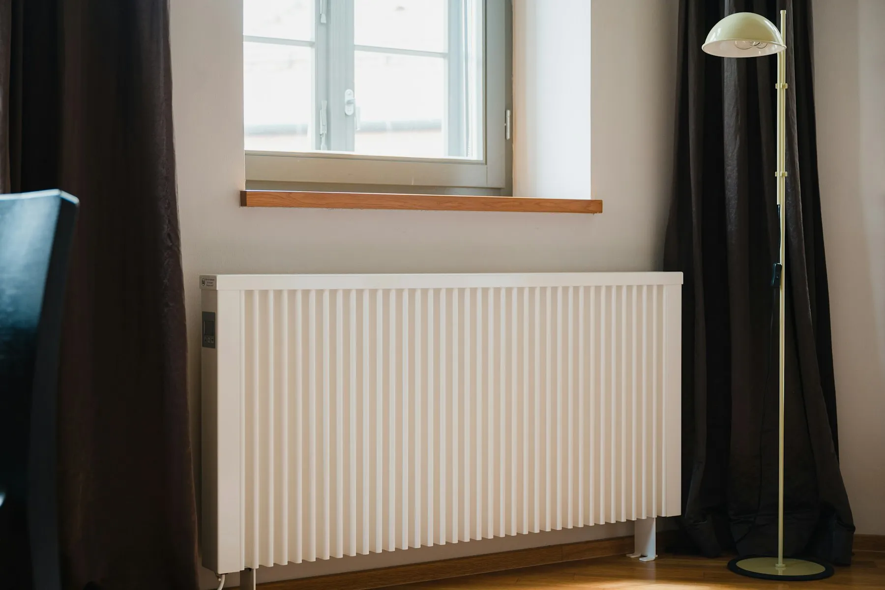 A white radiator under a window, with light falling through the glass