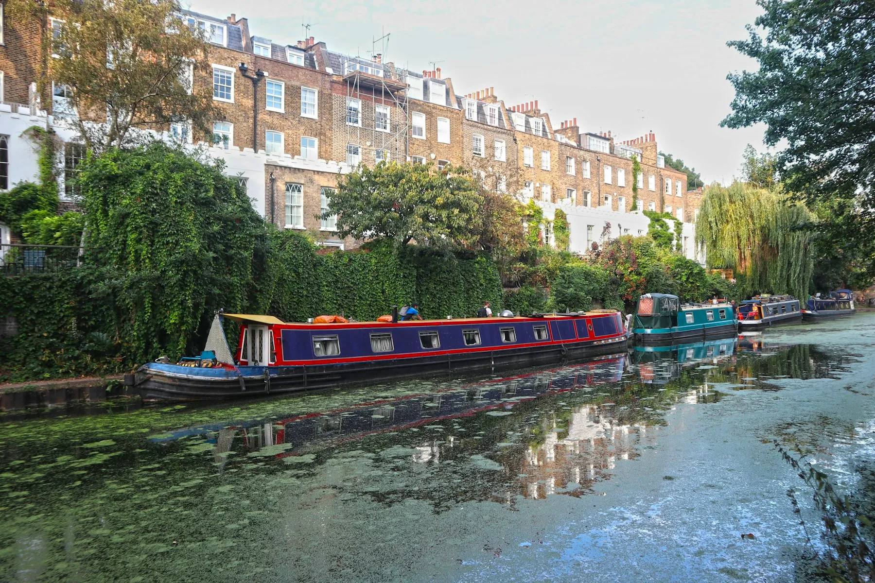 Narrowboats moored on the Regent's Canal below a terrace of tall Georgian houses