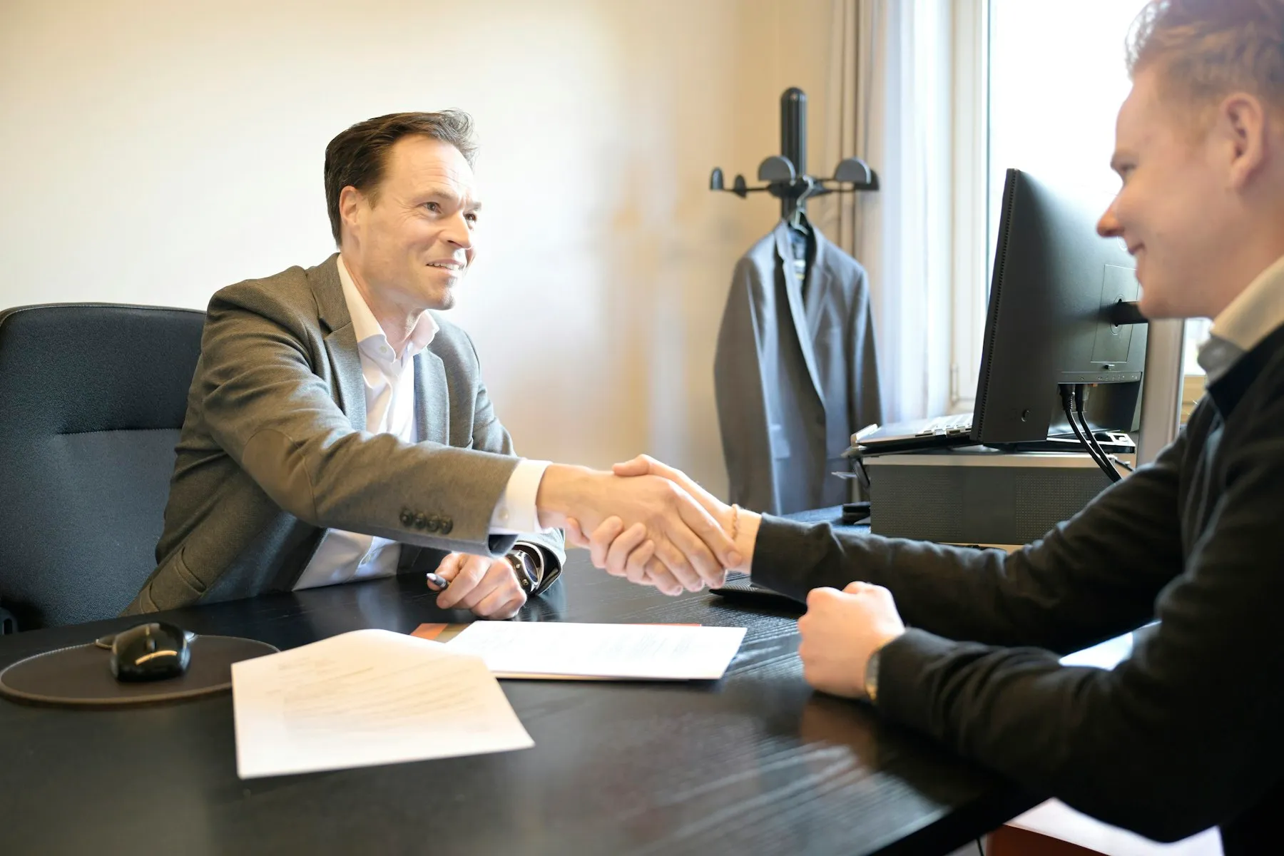 An agent and a client shaking hands across a desk